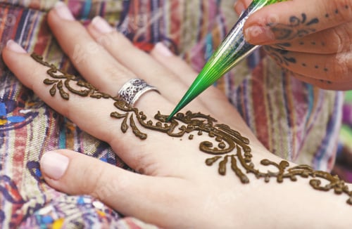 Preview: Artist painting traditional indian henna tattoo on woman hand