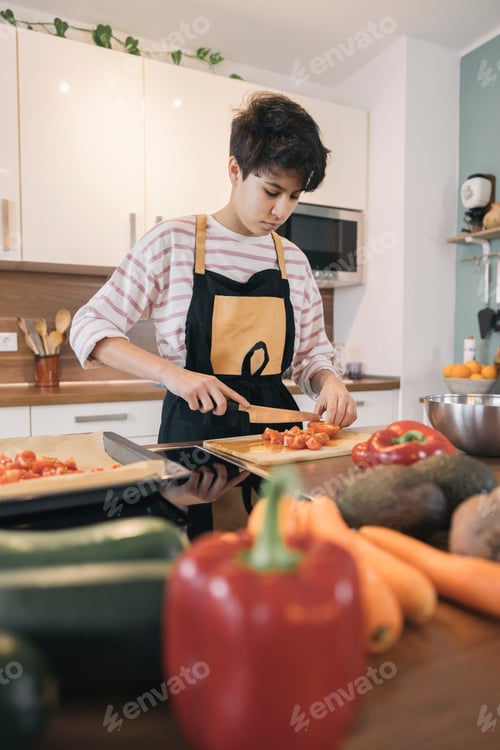 Preview: Teenage girl chopping tomatoes on cutting board, preparing healthy meal with fresh vegetables