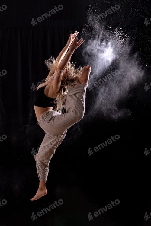 Preview: Young dancer performing a jump in studio photo session with a black background, ballet