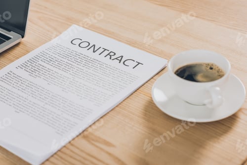 Preview: contract and cup of coffee on wooden table in office