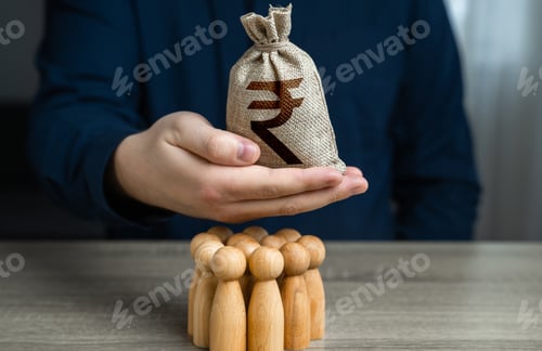 Preview: A man is holding a indian rupee money bag over a group of people figurines.