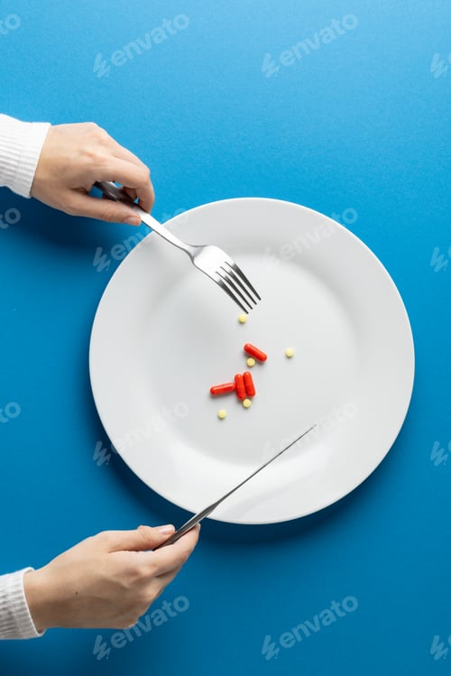 Preview: Vertical of hands holding fork and knife over plate with pills, on blue background with copy space