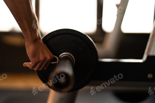 Preview: A man fixes spring clips for weights on dumbbells