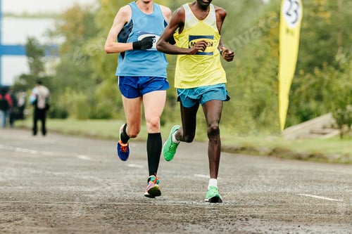 Preview: two runners running marathon race, front view, dressed in bright sports clothes