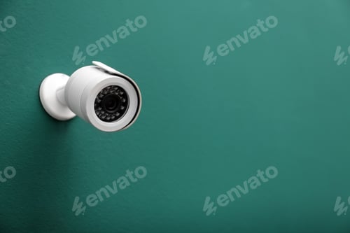 Preview: Modern CCTV security camera on green wall. Space for text