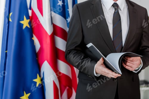 Preview: cropped view of diplomat holding folder near flags