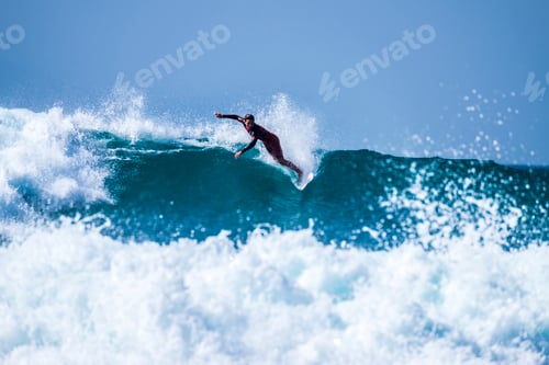 Preview: teenager surfing at the wave in tenerife playa de las americas - red wetsuits and beautiful