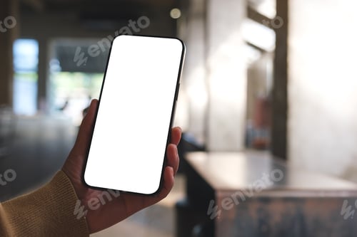 Preview: Mockup image of a woman holding and using mobile phone with blank desktop in cafe
