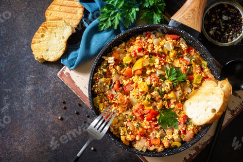Preview: Turkish cuisine. Menemen Scrambled eggs in a cast iron frying pan on a stone countertop.
