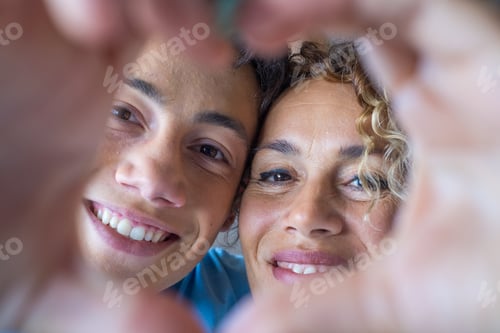 Preview: Portrait of couple of mom and son together a home making a heart love shape with their fingers