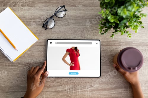 Preview: Millennial black woman with coffee cup using tablet for online shopping on wooden table, top view
