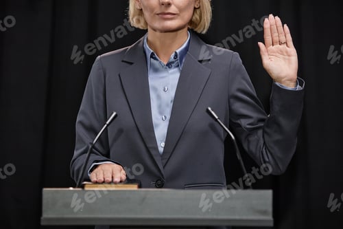 Preview: Female Politician Raising Hand Taking Oath to Uphold Constitution at Podium Indoors