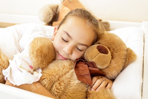 Preview: girl lying on bed with big brown teddy bear