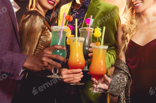 Preview: cropped view of friends holding alcohol cocktails on party