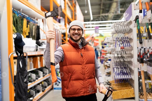 Preview: a man in a construction hypermarket chose an ax for cutting trees