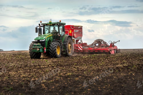 Preview: Farmers sow using a tractor with a seeder in a plowed field