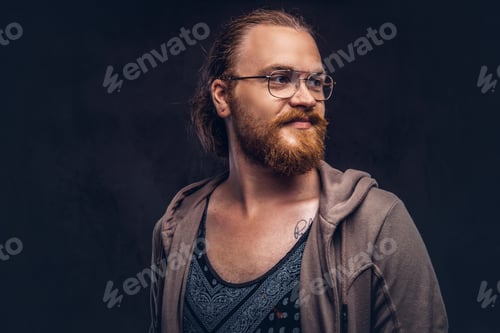 Preview: Portrait of a redhead hipster male in a studio. Isolated on the dark background.