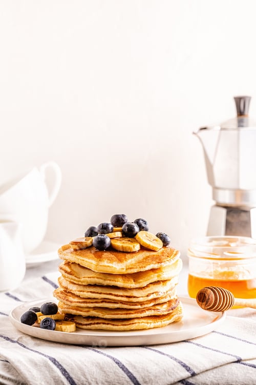 Preview: Pancakes with banana, blueberries on white plate.