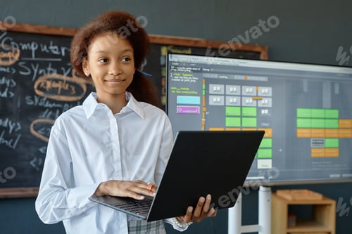 Preview: Smiling Black Teen Girl Holding Laptop Giving Presentation on IT in Class