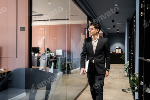 Preview: man in glasses and business suit working in office holding laptop coworking space