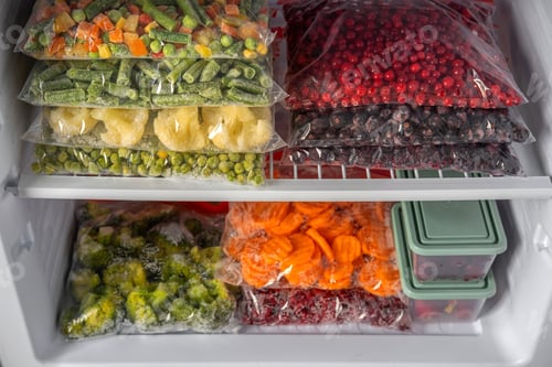 Preview: Plastic bags with different frozen vegetables and berries in refrigerator.