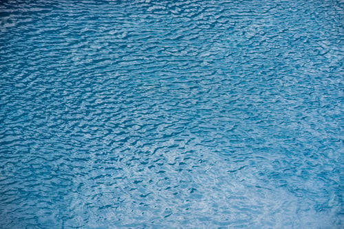 Preview: Water with small waves and raindrops on a pool with blue texture background
