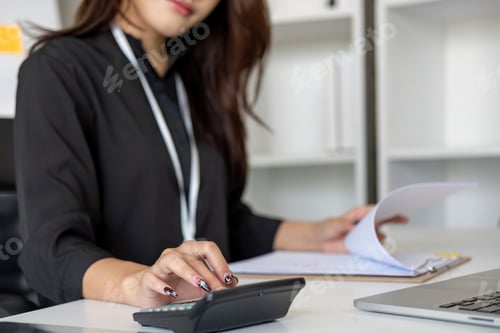 Preview: Close up Business woman using calculator and laptop for do math finance on wooden desk in office and