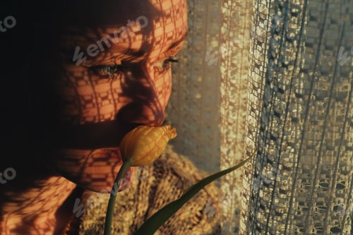 Preview: portrait of a woman standing next to a window, sunset through curtain cast a shadow on her face