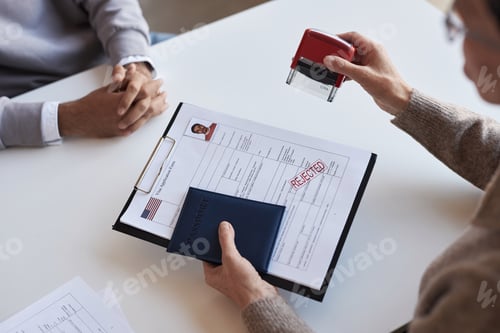 Preview: Close-up of mature female manager putting rejection stamp on filled form