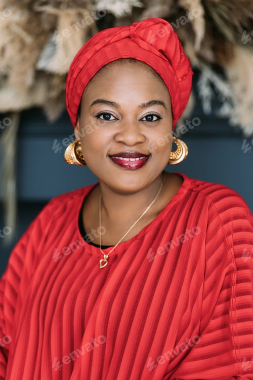 Preview: African woman with bright makeup and stylish jewerly, wearing red dress and ethnic headwrap, posing