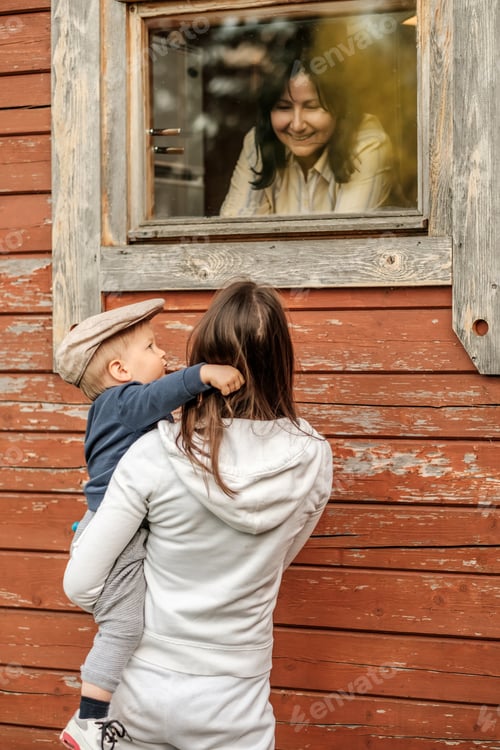 Preview: One year old baby boy with his mother outdoors looking at window