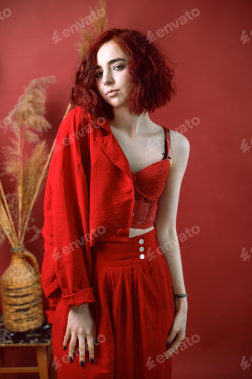 Preview: Fashionable young woman in a red suit. Red background.