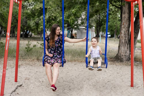 Preview: Mom swinging her baby boy in swing outdoor. Mother and her child having fun together outdoor. Happy