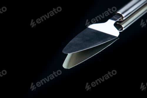 Preview: Close up view of kitchen cake slicer lying on black background with free space