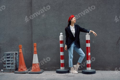 Preview: Fashion woman standing leaning against a wall street against a background of the city road works