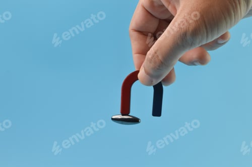 Preview: Man hand holding a magnet isolated on a blue background