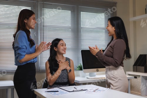 Preview: Businesswomen celebrating colleague success clapping hands in office