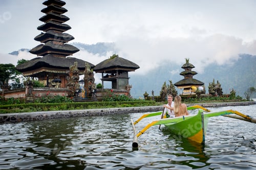 Preview: Young couple paddling on a wooden boat at Pura Ulun Danu Bratan