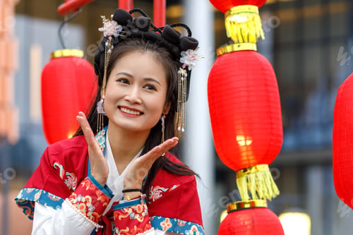 Preview: Young Asian woman in traditional red Chinese costume walks in the park. Celebrating Chinese New Year