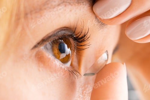 Preview: Close up young woman wearing a contact eye lens