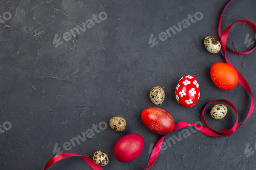 Preview: top view colored easter eggs with quail eggs and red bow on dark surface spring colour easter