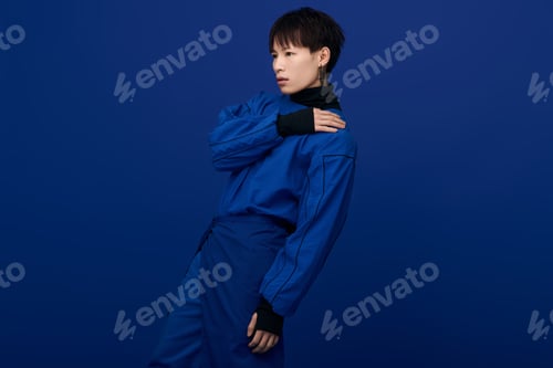 Preview: Striking young asian man poses confidently against a vibrant blue backdrop showcasing modern style