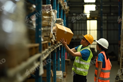 Preview: Two storehouse employees wearing hard hats and reflective jackets loading.