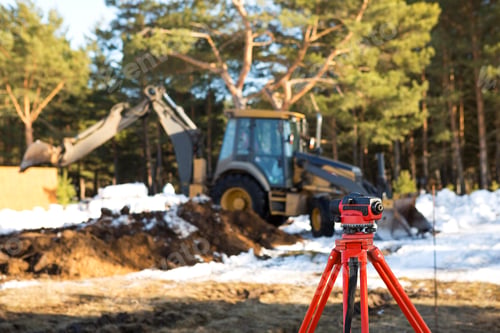 Preview: A geodesic level stands in front of a bulldozer for excavating a pit at a construction site