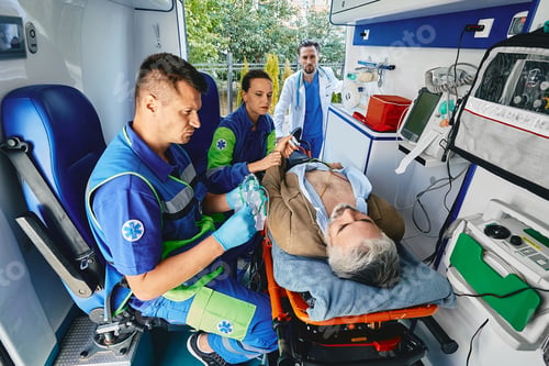 Preview: Paramedics performing electrocardiogram on mature patient lying on gurney with electrodes placed on