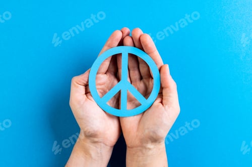 Preview: Close up of hands of caucasian woman holding peace sign with copy space on blue background