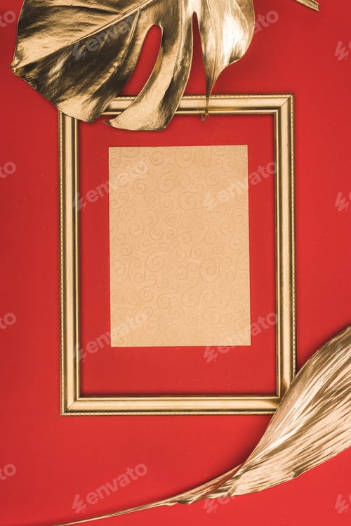 Preview: top view of golden photo frame, leaves and blank paper isolated on red