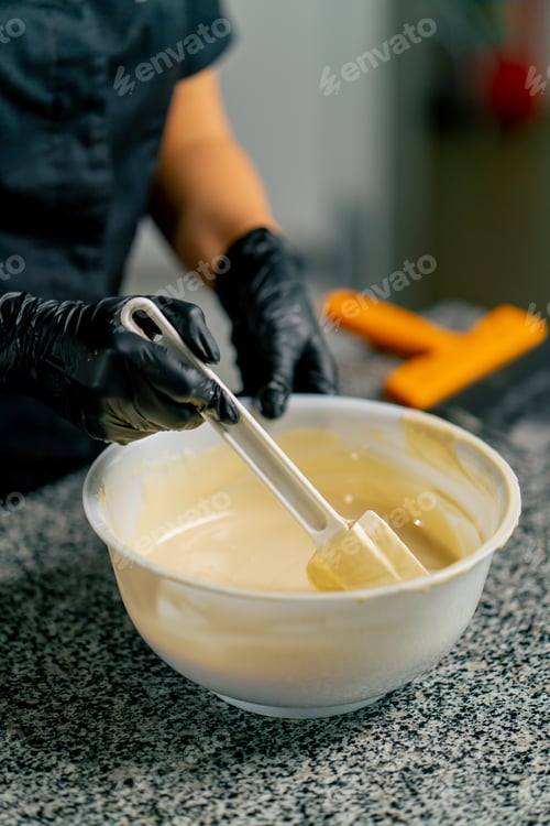 Preview: Girl chocolatier using silicone spatula mixes chocolate for making desserts in a confectionery shop