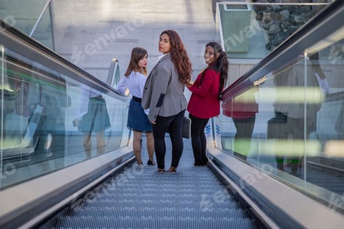 Preview: Three businesswomen on the escalators in the business building on their way to work.