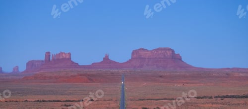 Preview: Scenic Road in the Dry Desert with Red Rocky Mountains in Background.